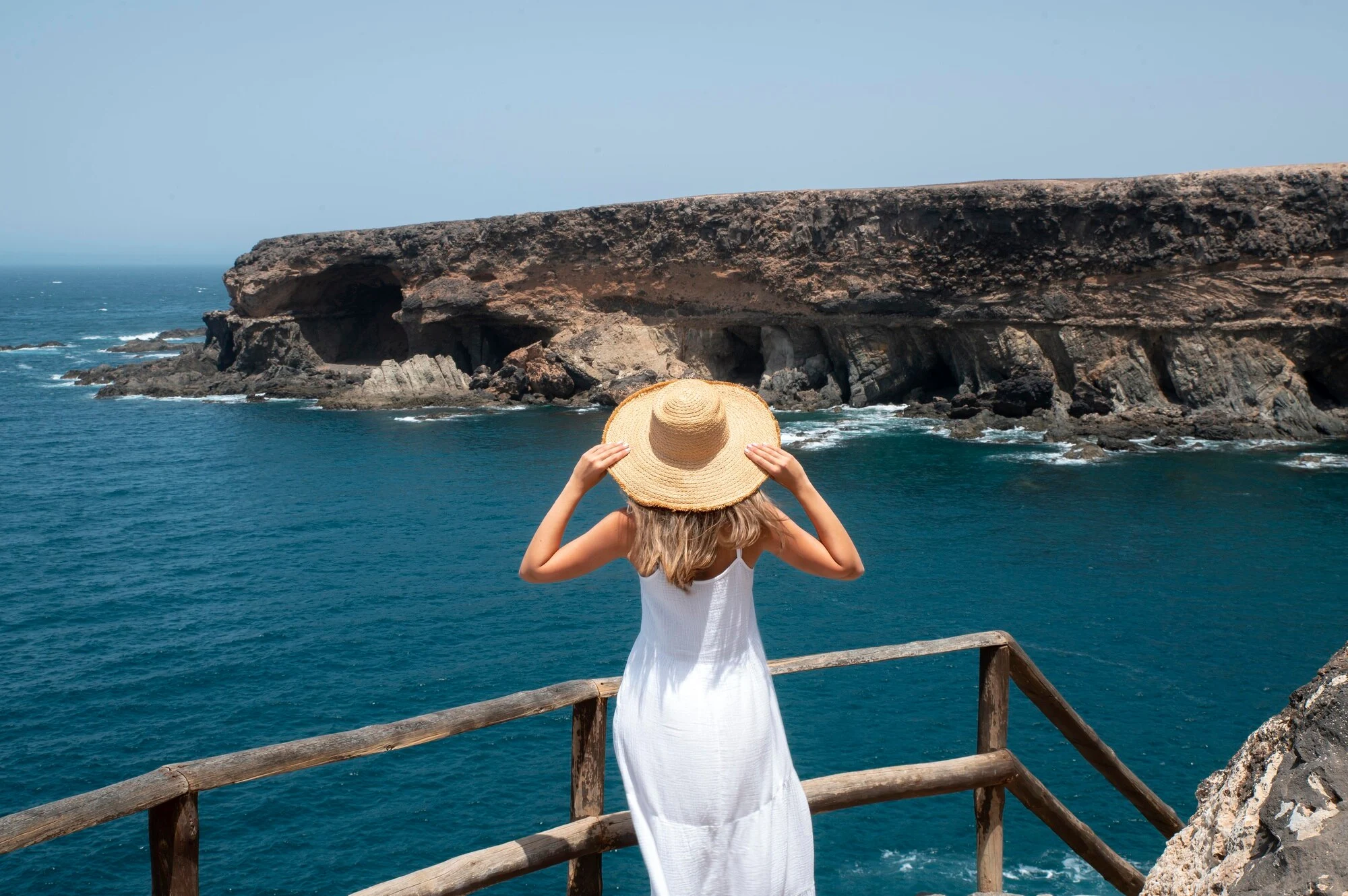 Vista trasera de una mujer joven mirando el océano, ilustrando la cartelería digital en Canarias